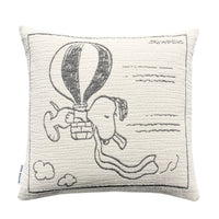 Square white cotton Maison Deux Peanuts Cushion featuring a black line drawing of Snoopy flying in a hot air balloon, with the signature Schulz in the upper right corner.