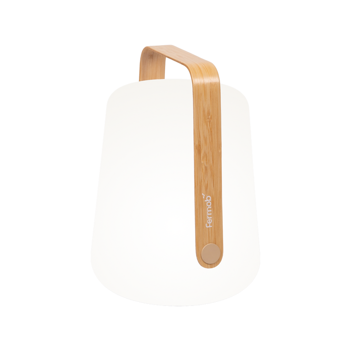 The Fermob Balad2 Outdoor Light, Bamboo, H38 is a modern, minimalist lamp with a rounded base and curved bamboo handle—perfect as a portable light for your garden or patio.