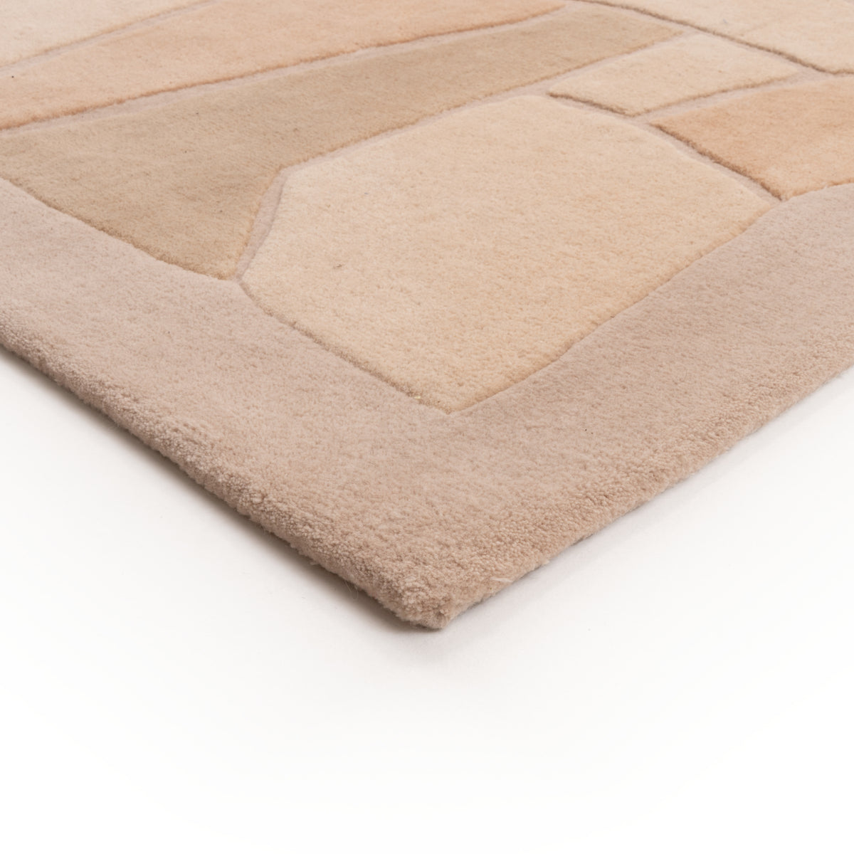 A beige, hand-tufted Ligne Roset Bojagi rug featuring an abstract geometric pattern with carved borders.