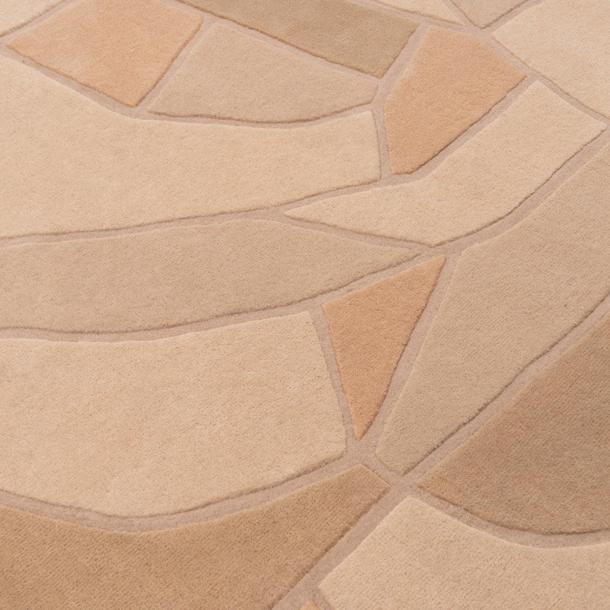 A Ligne Roset Bojagi area rug featuring a hand-tufted tan and beige carved, abstract geometric pattern of organic, leaf-like shapes.