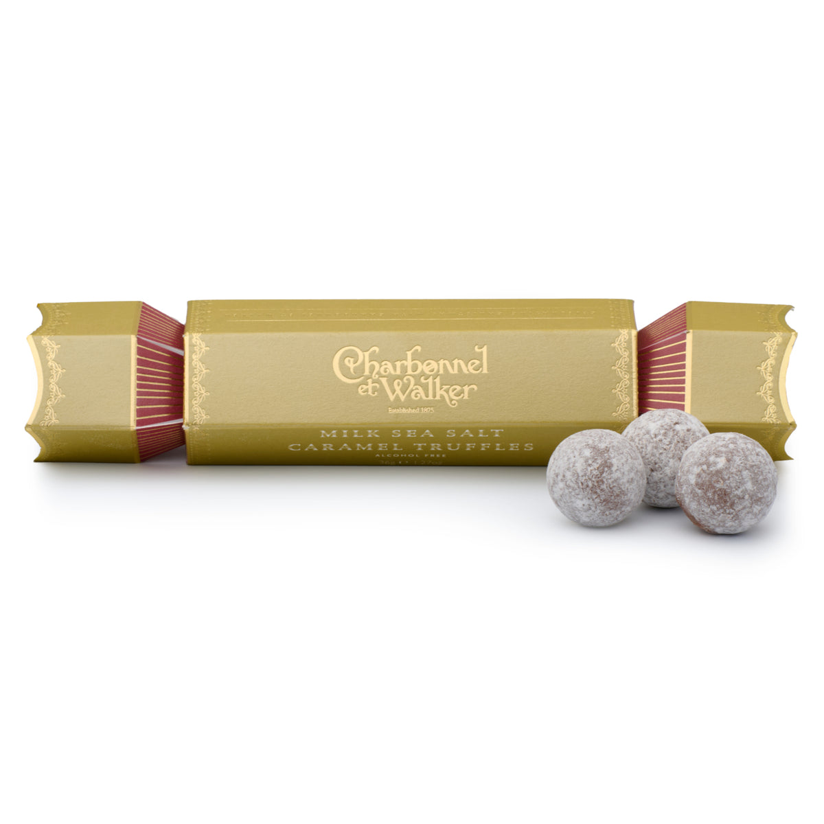 A gold Milk Sea Salt Caramel Truffle Cracker, 36g with red accents sits next to three Charbonnel & Walker salted caramel truffles dusted with powder.