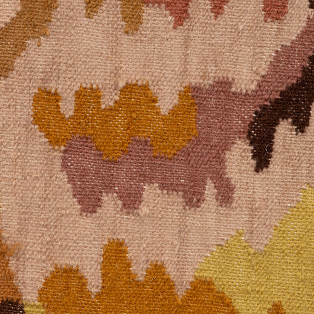 A close-up of a Ligne Roset Kimono rug, a hand-tufted New Zealand wool textile featuring geometric, jagged shapes in shades of beige, brown, gold, and muted red.