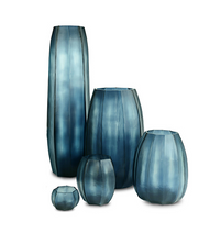Five Koonam Vases by Guaxs in ocean blue/indigo mouthblown glass, featuring semi-transparent finishes and varying heights and widths, are arranged together on a white background.