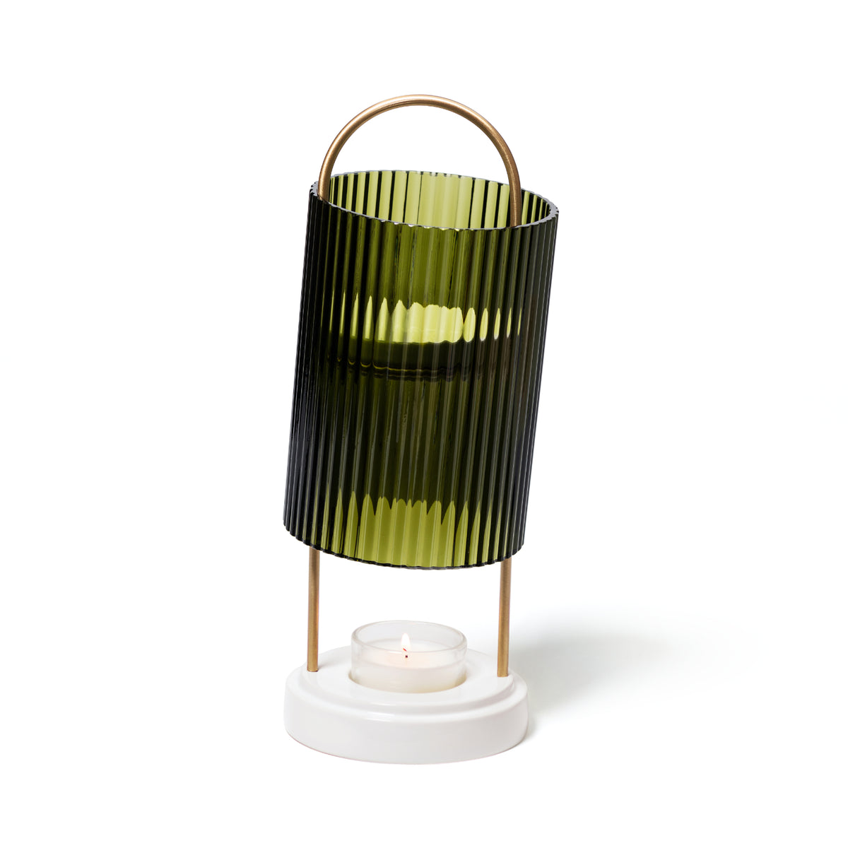 A dark green fluted glass Trudon La Promeneuse candle warmer on a white circular base with a lit tea light inside used for scented wax cameos.