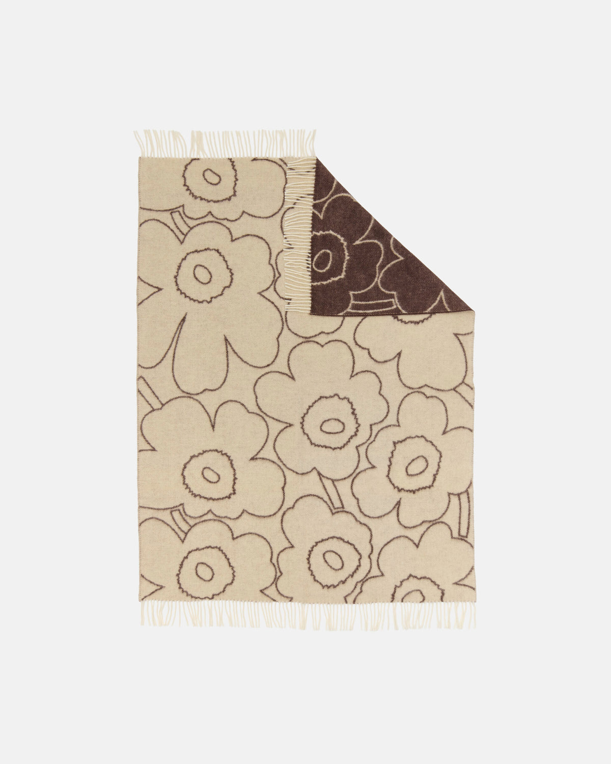 The Marimekko Piirto Unikko Blanket is a beige wool throw featuring a large, bold floral pattern outlined in brown. One corner is folded to reveal the reverse side with the same design in inverted colors. Inspired by Marimekko’s classic Unikko motif, this blanket is finished with fringe on the edges and is crafted from responsibly sourced fibers that meet the Responsible Wool Standard.