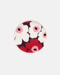 The Marimekko Unikko Plate 20cm is a round ceramic plate featuring the iconic bold floral Unikko pattern with large white and red flowers, black centers, and pink accents set against a dark background.