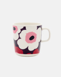 The Marimekko Oiva / Unikko Mug 4dl is a ceramic mug with a handle, showcasing Marimekko’s iconic bold floral pattern, featuring large white flowers with pink centers set against a dark background—perfect for anyone who loves distinctive Scandinavian design.