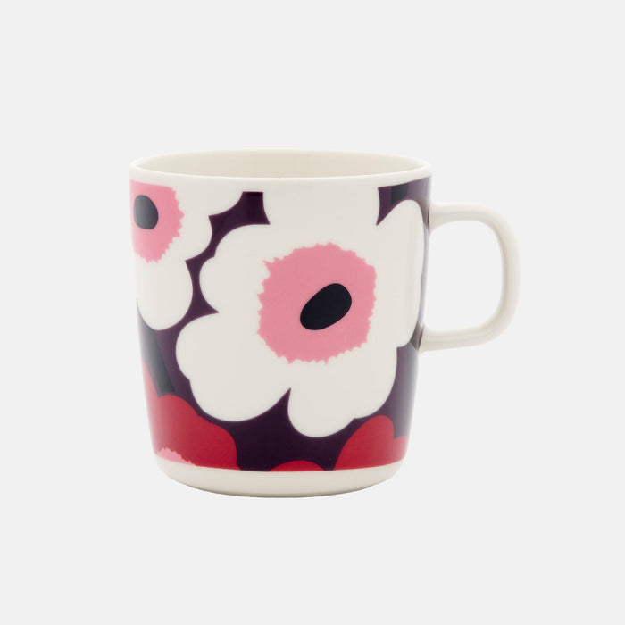 The Marimekko Oiva / Unikko Mug 4dl is a ceramic mug with a handle, showcasing Marimekko’s iconic bold floral pattern, featuring large white flowers with pink centers set against a dark background—perfect for anyone who loves distinctive Scandinavian design.