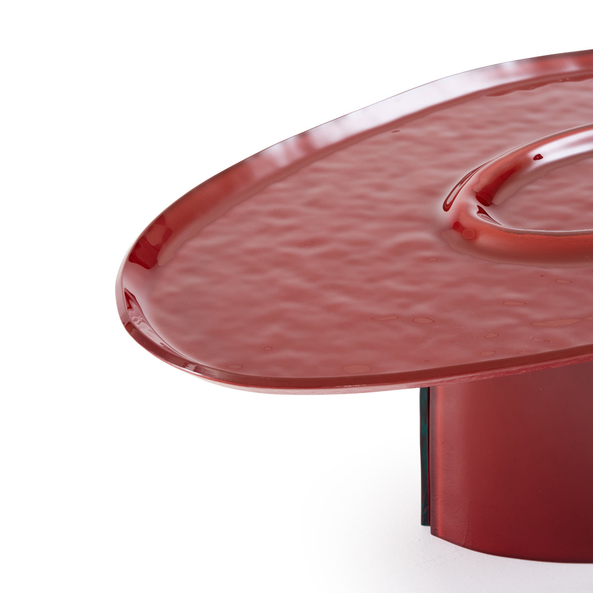 Oasi Low Table by Ligne Roset: a low, oval, hammered red lacquered glass table with an undulating surface and a central recessed depression.