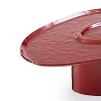 Oasi Low Table by Ligne Roset: a low, oval, hammered red lacquered glass table with an undulating surface and a central recessed depression.