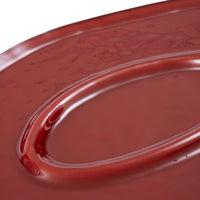 Close-up of a glossy, deep red oval Ligne Roset Oasi Low Table with a central recessed basin.