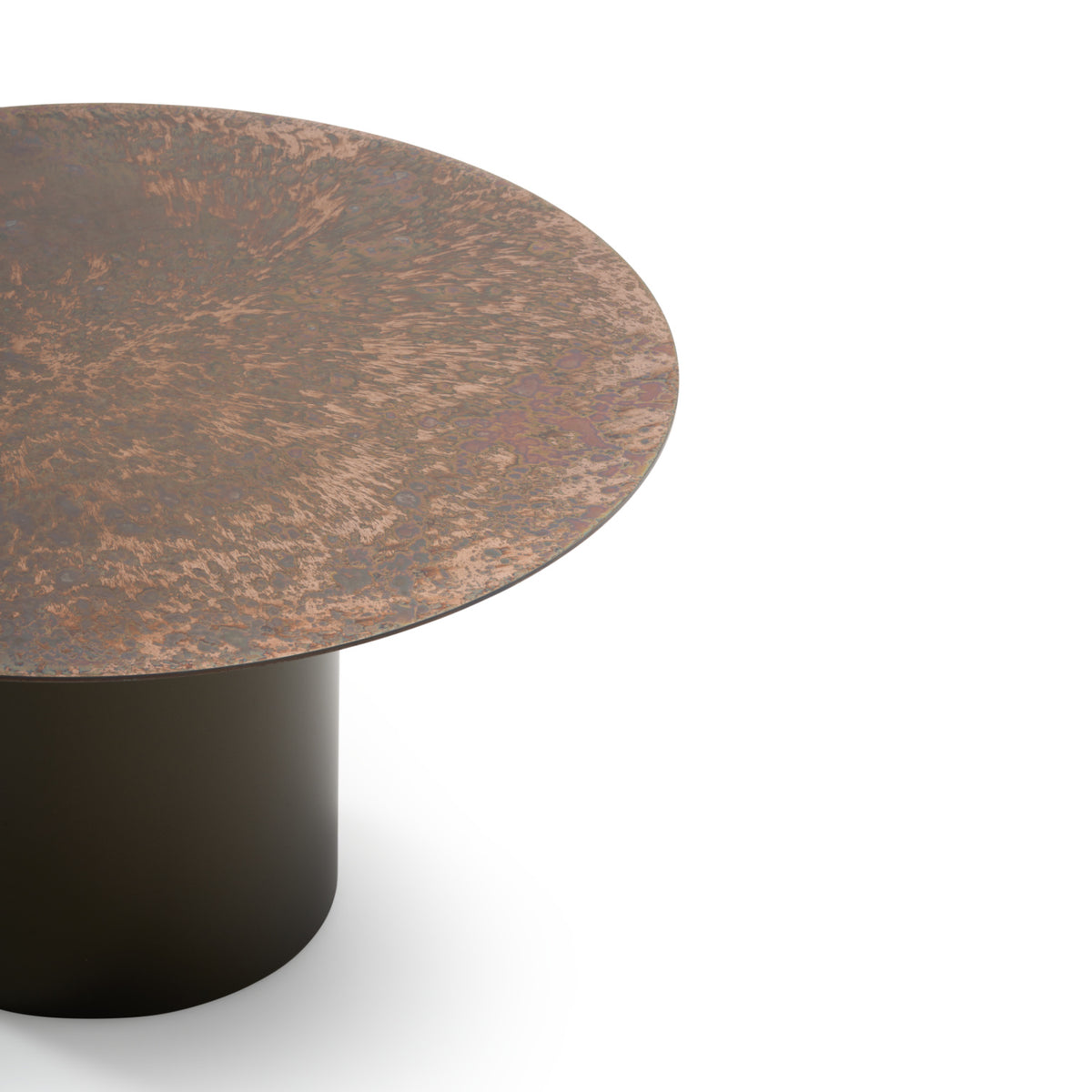 A close-up of the Oxydation Coffee Table by Ligne Roset, part of the collection designed by Kateryna Sokolova, featuring a textured, copper-toned oxidised metal top and a cylindrical black base, shown against a white background.