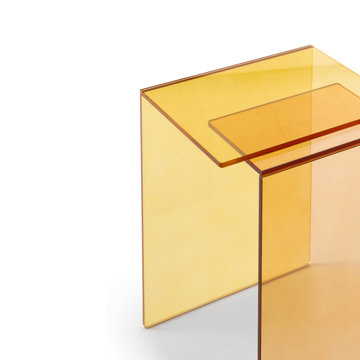 A close-up of the Patchs Occasional Table by Ligne Roset, featuring modern, translucent amber acrylic with clean, minimalist lines and transparent yellow tones—perfect for a contemporary interior—set against a white background.