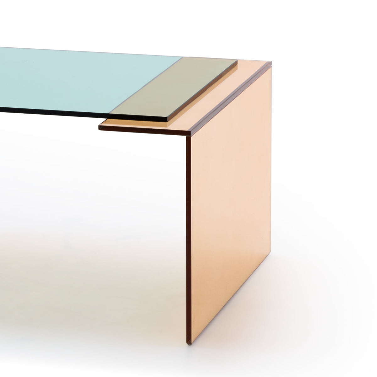 The Patchs Low Table by Ligne Roset is a modern piece featuring clean, minimalist lines, a layered green-tinted tempered glass top, and a distinctive tan-colored side panel.
