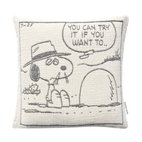Square Maison Deux Peanuts Cushion featuring a woven comic strip panel of Snoopy wearing a hat and sitting by a hole, with a speech bubble that reads, YOU CAN TRY IT IF YOU WANT TO.