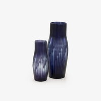 Two purple mouth-blown Purple Rain vases by Ligne Roset, featuring vertical ridges and gradient patterns—one tall, one short—are displayed on a plain white background, ideal as contemporary decorative pieces for any space.