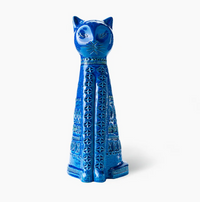 The Bitossi Standing Cat Figure is a tall, bright blue ceramic figurine with geometric and floral patterns, pointed ears, and a stylized face, inspired by Rimini Blu designs and shown against a white background.