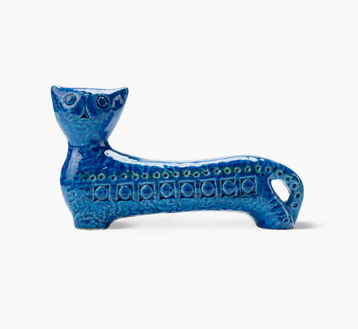 The Bitossi Long Cat Figure is a blue ceramic sculpture with circular patterns and a textured surface, featuring a mid-century-inspired design with a long body, short legs, and small head reminiscent of Rimini Blu.