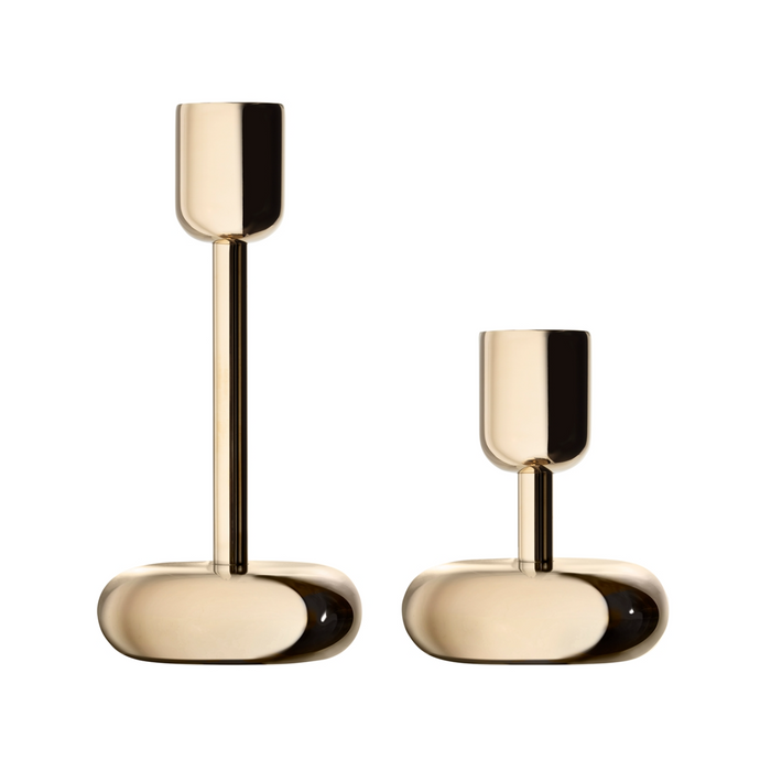 The Nappula Brass Candle Holders, 2 Pack, features two modern gold-colored brass holders with rounded bases and cylindrical stems—one taller—displayed on a white background.