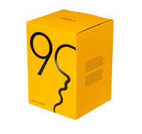 A bright yellow box with bold black abstract lines forming '90' and a face profile, labeled Alvar Aalto Bubble Vase by Iittala, features text on the side—a tribute to Alvar Aalto’s iconic design.