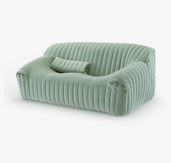 The Sandra Small Sofa by Ligne Roset is a modern light green velvet loveseat with retro-inspired quilted ribbed texture, rounded edges, and a matching rectangular cushion.