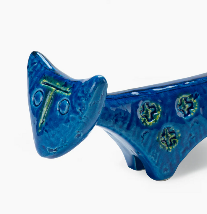 A close-up of the Cat Figure by Bitossi, featuring simple carved facial features and star-like patterns. Its glossy blue surface with green accents highlights classic mid-century design.