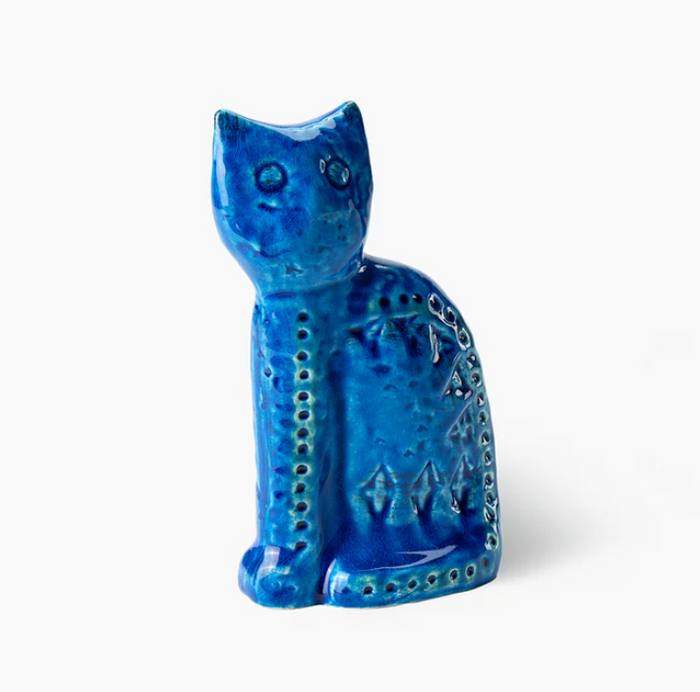 The Seated Cat Figure by Bitossi is a blue ceramic figurine with a glossy finish, mid-century design, and indented geometric patterns, inspired by Rimini Blu. The cat sits upright against a plain white background.