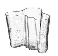 The Alvar Aalto Bubble Vase features a clear, wavy-edged design with an organic shape and small air bubbles, celebrating the iconic style of Alvar Aalto.