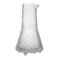 The Ultima Thule Pitcher 50cl Clear is a Nordic-inspired glass pitcher with a wide base, narrow neck, and spout. Its clear textured surface features vertical lines and bubble-like details reminiscent of classic Iittala designs.