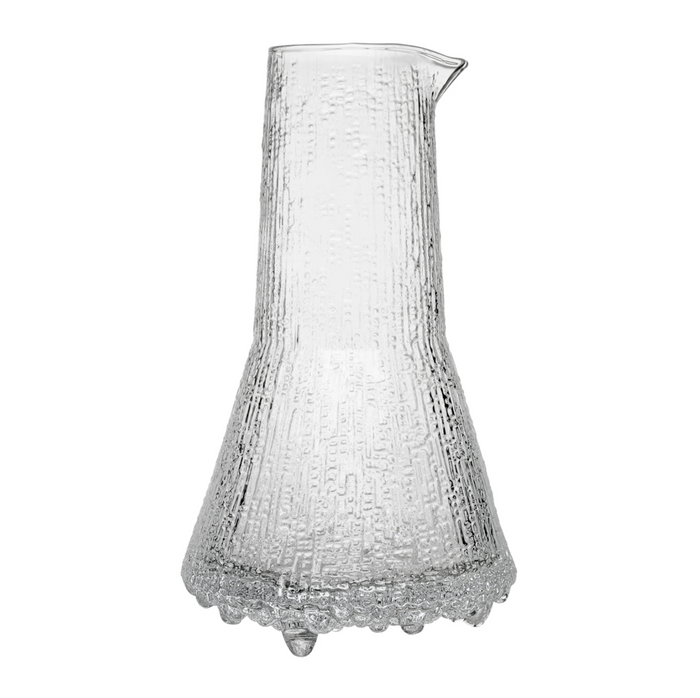 The Ultima Thule Pitcher 50cl Clear is a Nordic-inspired glass pitcher with a wide base, narrow neck, and spout. Its clear textured surface features vertical lines and bubble-like details reminiscent of classic Iittala designs.