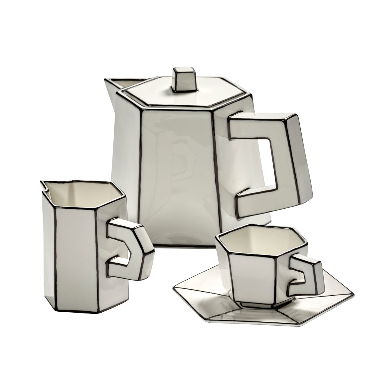 Three white ceramics—a Carte Blanche Teapot by Serax, a creamer, and a cup with matching saucer—stand out with bold black outlines and exude modern artistry in fine bone china. Each Serax piece showcases angular, geometric forms and a strikingly contemporary design.