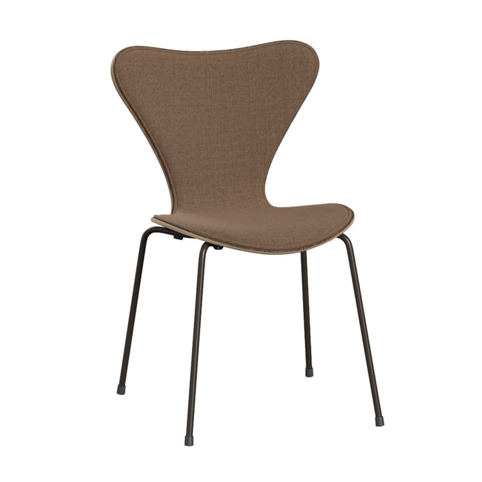 The Series 7 Chair, Front Upholstered in Technicolor Fabric by Fritz Hansen features a brown fabric finish with a gracefully curved backrest and seat, supported by four slender black metal legs. Drawing inspiration from Danish design principles and echoing Arne Jacobsen’s iconic aesthetic, this minimalist and modern chair is ideal for dining or office settings. The chair is showcased against a plain white background.