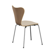 The Series 7 Chair by Fritz Hansen, featuring front upholstery in Technicolor fabric, showcases a modern wooden form with a curved backrest and seat inspired by Danish design, supported by four slender metal legs and displayed at an angle against a white background.
