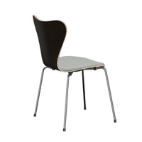 The Series 7 Chair by Fritz Hansen, shown front-upholstered in Technicolor fabric, features a modern Danish-inspired design with a gracefully curved dark wooden backrest, a light gray cushioned seat, and four slender metal legs, presented from a rear side angle against a white background.