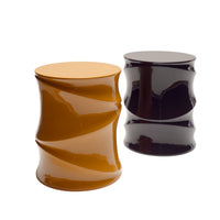 Two glossy, cylindrical Simeti Occasional Tables by Ligne Roset—one in mustard yellow and the other in dark purple—stand side by side against a white background. Handcrafted in Vietnam with a lustrous lacquer finish and featuring unique twisted designs, these eye-catching tables make a bold statement in any space.