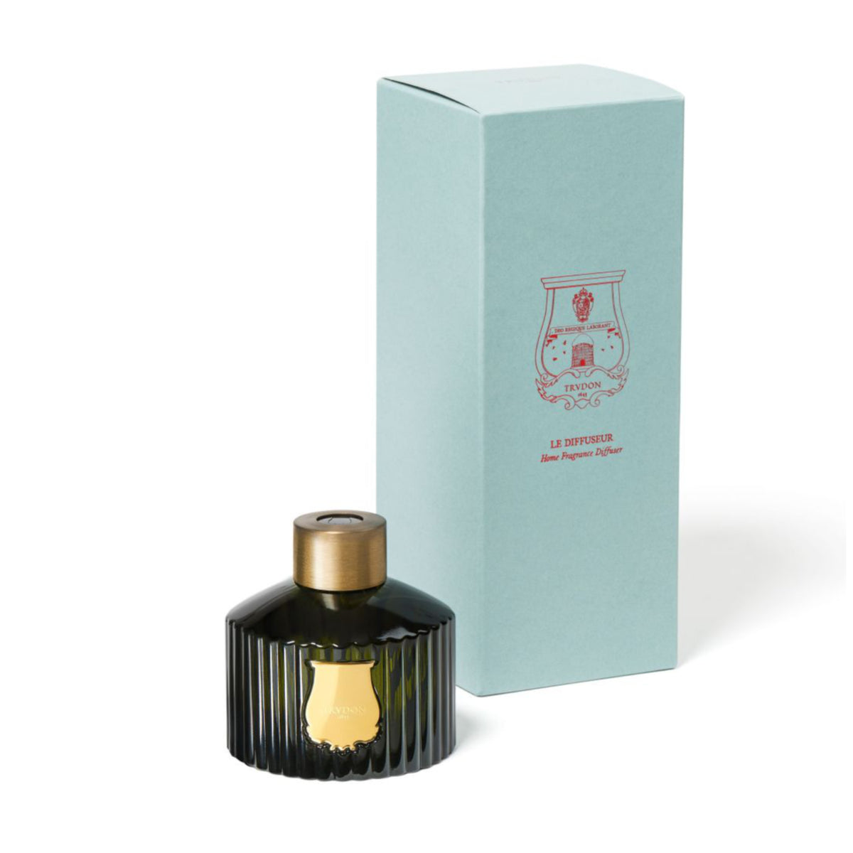 A black ribbed glass bottle with a gold cap rests next to a light blue box adorned with a red crest and lettering. The Trudon Diffuser 350ml by Trudon is an elegant luxury home fragrance set, exuding sophistication and style. Both items are displayed on a white background.