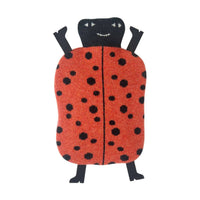 The Donna Wilson Ladybird Hot Water Bottle features a soft, plush design with a red, black-spotted body, a smiling black head, and black arms and legs. It is shown lying on a white background.