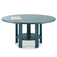 The Saba Anam Dining Table features a round teal top, six cylindrical legs, and a lower circular shelf. Its smooth surface holds two closed books, making it a stylish contemporary choice for modern interiors.