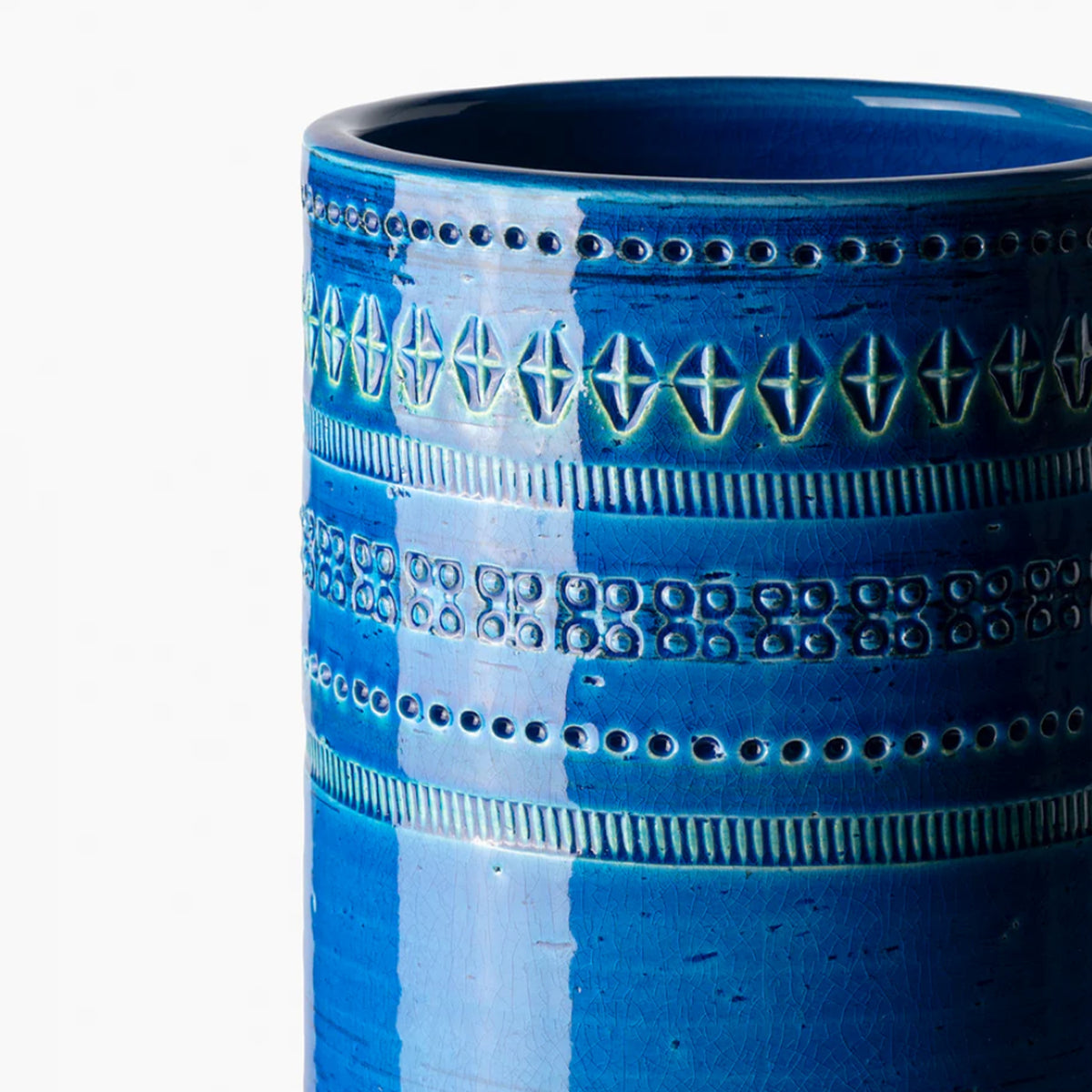 A close-up of the Bitossi Cylindrical Vase 30cm shows its tall blue ceramic form with glossy, textured geometric patterns—details inspired by Rimini Blu mid-century design and rich blue hues.