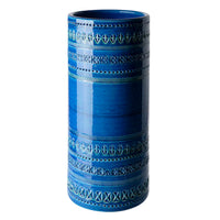 The Bitossi Cylindrical Vase 30cm is a tall blue ceramic piece inspired by Rimini Blu, featuring geometric patterns and textured bands in varied blue shades—a striking example of mid-century design.