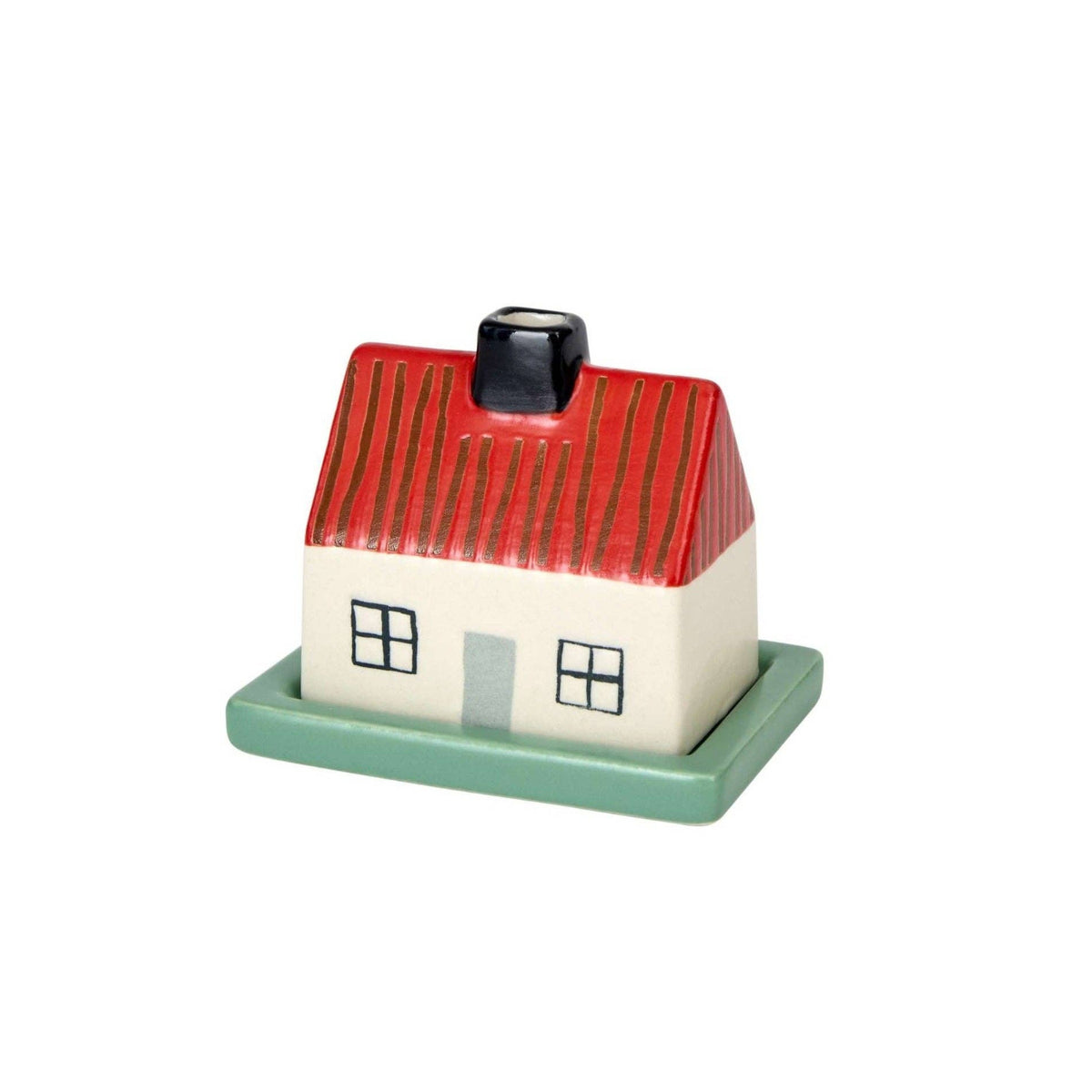 Introducing the Donna Wilson Little Hiding House by Donna Wilson—a small stoneware butter dish crafted in the shape of a house, complete with a red roof, white walls, black chimney, green door, and four charming windows. Set on a green rectangular base, this delightful piece features a hidden compartment that’s ideal for stashing tiny treasures or using as a keepsake box.