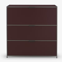 The Dita Secretaire Desk by Ligne Roset is a modern burgundy filing cabinet with three drawers, a minimalist metal frame, and sleek handles. It stands on a flat surface against a plain white background—a refined storage solution.
