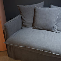 The Gervasoni Ex-Display Ghost Single Sofa Bed 11, a modern gray fabric loveseat with a removable cover and two large pillows, features soft cushions, one left armrest, and minimalist design against a dark wall.