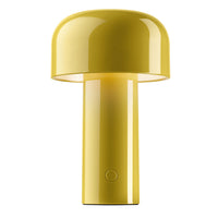 The Flos Bellhop Portable Lamp, IP54, is a modern yellow rechargeable table lamp with a glossy mushroom-shaped shade, cylindrical base, and small round button. This cordless lighting option features a minimalist contemporary design.