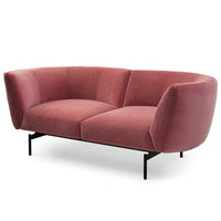 The Saba Rendez-Vous 2-Seater Sofa features a modern curved design in pink fabric, thick angled armrests and backrest, and slender black metal legs—an eye-catching piece of contemporary furniture.