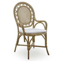 The Romantica Wicker Chair by Sika Design features a rounded back, decorative weave, curved arms, and a white cushion—an elegant handmade rattan piece perfect for any space.