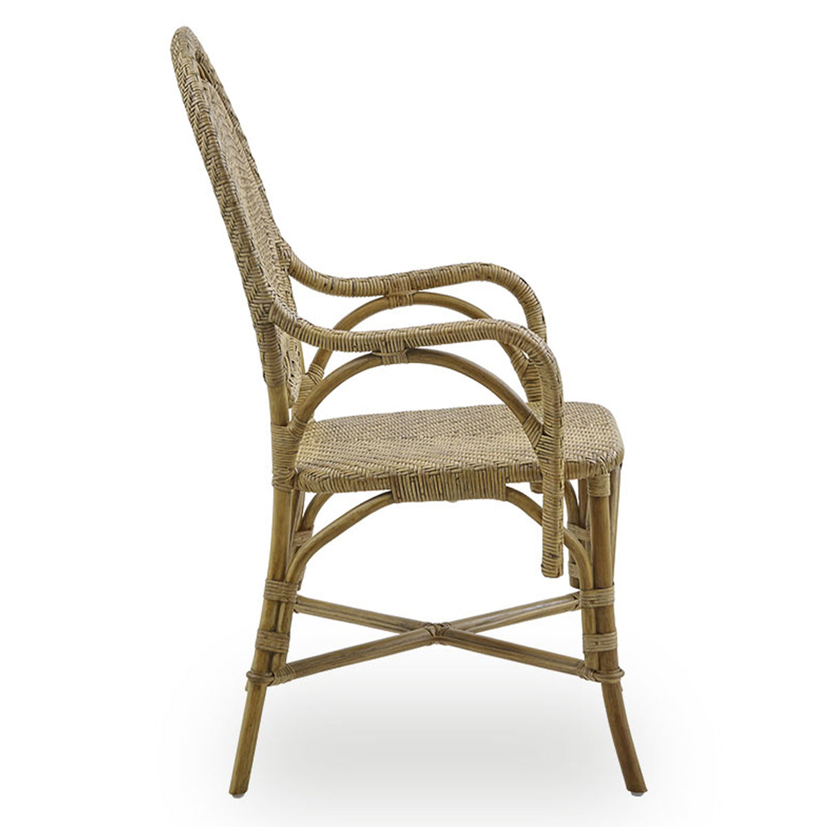 Side view of the Romantica Wicker Chair by Sika Design—a handmade dining chair crafted from natural-colored rattan with a woven seat, curved backrest, armrests, four legs, and sturdy crossbar supports.