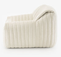 Side view of the Sandra Armchair, Vidar by Ligne Roset—a modern, low-profile lounge chair in soft white fabric with deep horizontal channel tufting—shown against a plain white background.