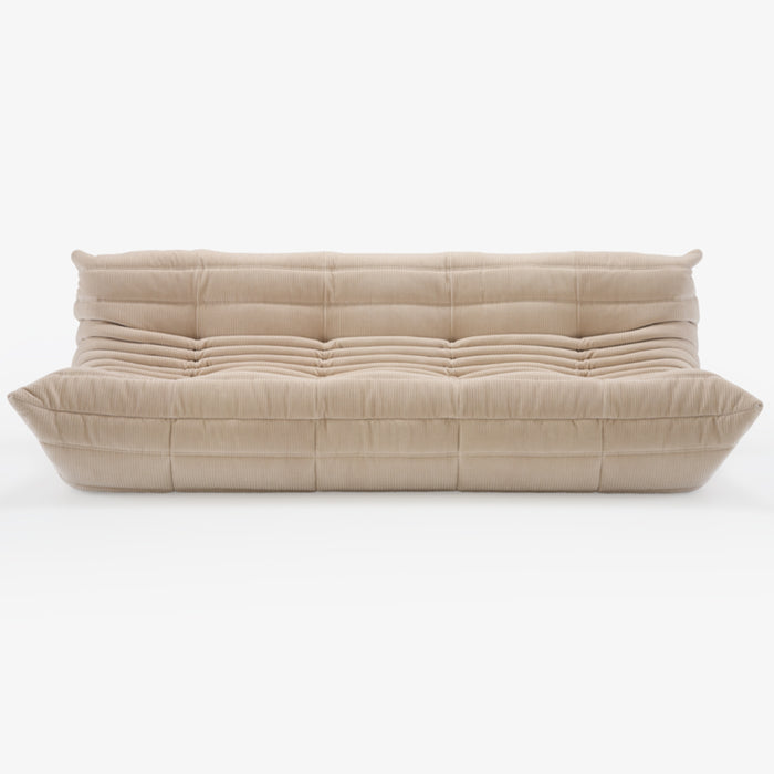 A modern, plush beige Togo Very Large Sofa by Ligne Roset, crafted in Phlox fabric and inspired by Michel Ducaroy’s iconic design, featuring deep horizontal and vertical tufting, a low-profile silhouette, and overstuffed cushions—shown here on a white background.