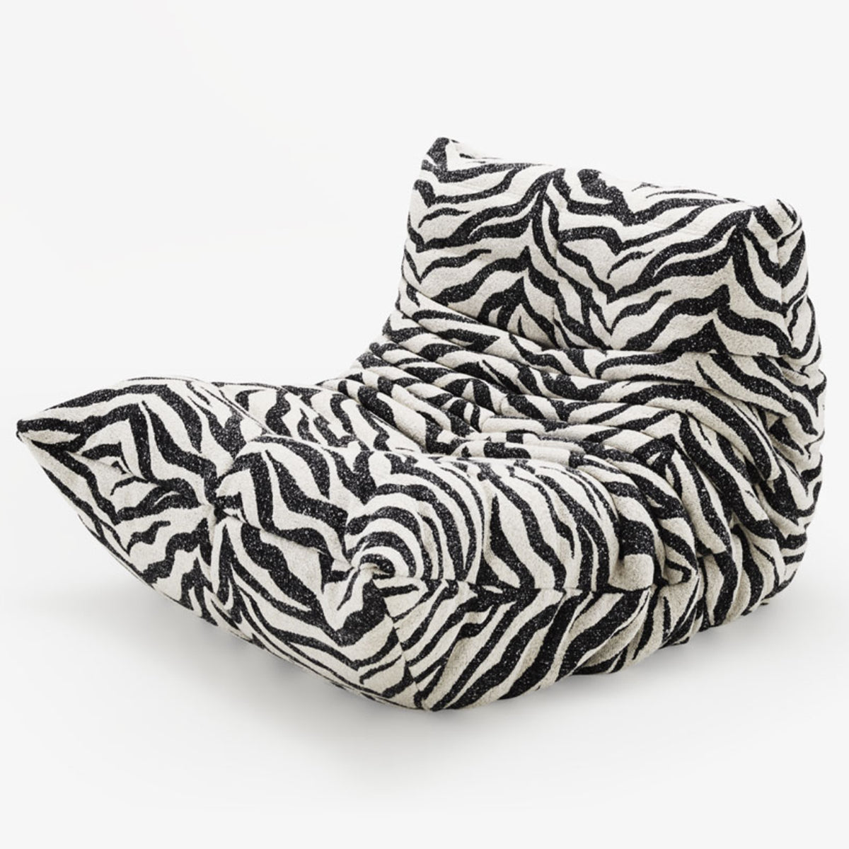 A modern Togo Fireside Chair, Tablu by Ligne Roset is displayed against a plain white background, featuring a plush, ruched design and a striking black-and-white zebra print pattern. This iconic piece embodies the essence of modular seating with its inviting form and contemporary flair.